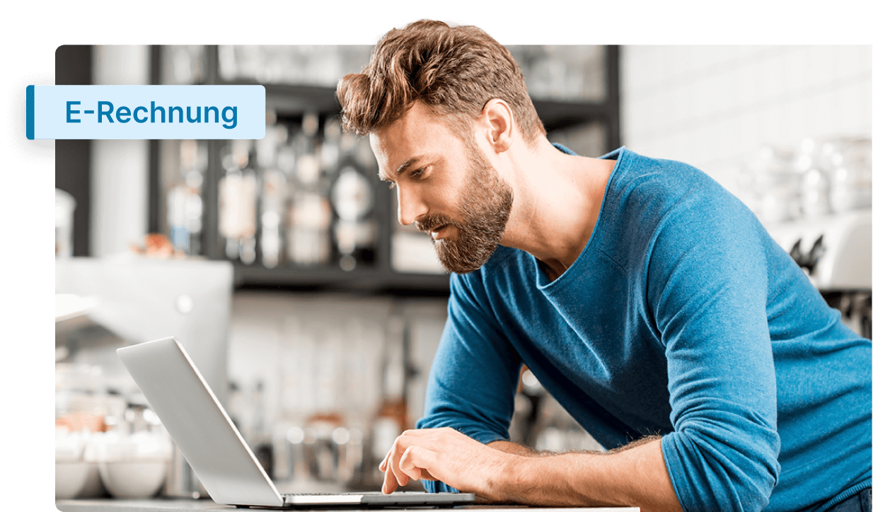 Ein Mann in einem blauen Pullover arbeitet konzentriert an seinem Laptop und recherchiert Informationen über E-Rechnungen in einer modernen Büro- oder Caféumgebung.